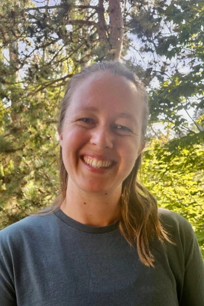 Midwife Britney Zell smiles into the camera while standing in front of a tree in Washington state
